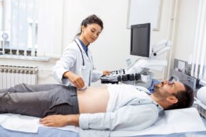 A doctor performing an ultrasound on a man laying on a medical table in an exam room.