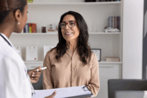 A woman with glasses speaking to a healthcare provider about her imaging options.