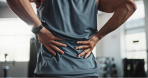 A person with their hands on their back indicating they have back pain or a spine injury.