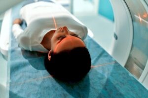 A woman laying on her back while she enters a CT scan tube.