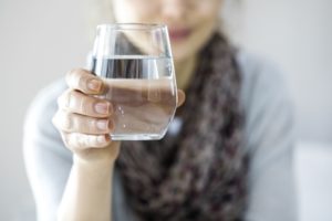Woman holding a glass of water that she is about to drink. 
