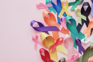 A pale pink background covered in a variety of cancer awareness ribbons. 
