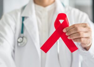 The torso of a doctor with a stethoscope holding out a red Stroke Awareness Month ribbon.